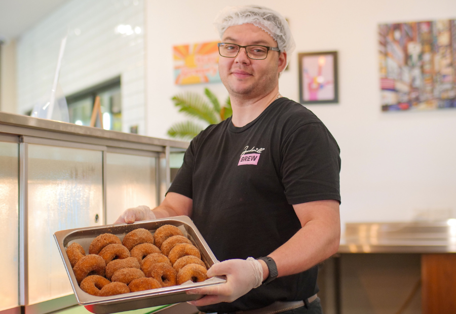 Employee at social enterprise cafe holding a tray full of donuts