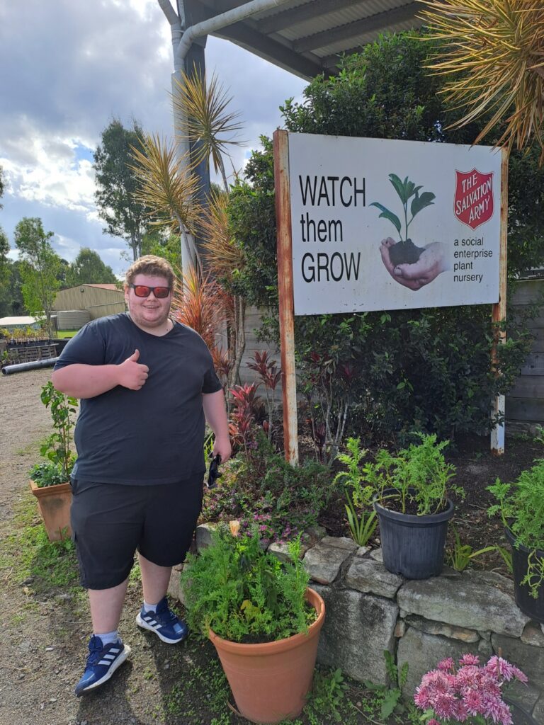 Rob in front of the nursery sign with right thumb up and smiling at camera