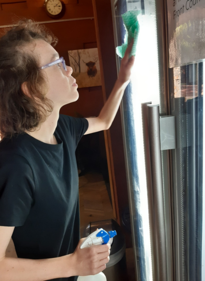 Rhiannon cleaning a fridge window during her work experience, an employment opportunity for teenagers with disability.